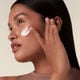 "A model applying the Shiseido Bio-Performance Advanced Super Revitalizing Cream applied on her cheek as she looks away from the camera, showcasing the rich-textured cream.  "