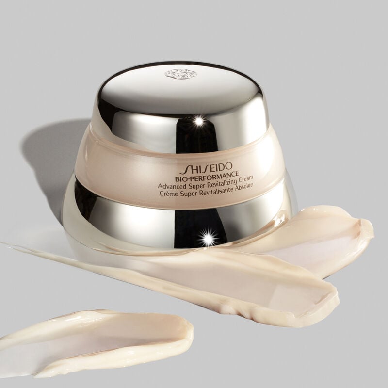 "A jar of the Shiseido Bio-Performance Advanced Super Revitalizing Cream against a gray background. There are multiple swatches of the rich-textured cream in front of the bottle.  "