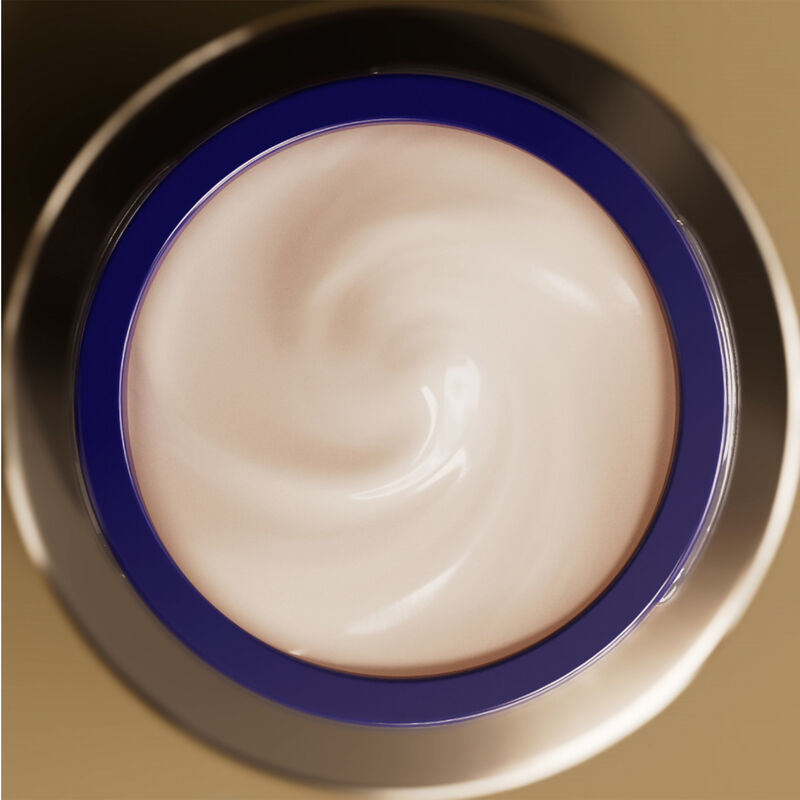 A round, open jar of Shiseido Vital Perfection Uplifting and Firming Advanced Cream from above, filled with a light cream-colored product swirled inside.  